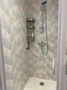 a shower in a bathroom with a tiled wall at CORALINES - Villa en residence in Saint-Cyprien