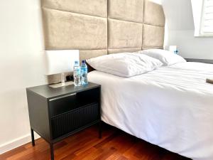 Una cama con una mesita de noche con dos botellas de agua. en Apartament Aviator en Mielec