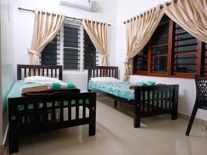 科钦PRAKRITI HOMESTAY Fortkochi Air Conditioned Rooms的有窗户的房间里有两张床