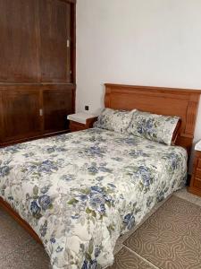 a bedroom with a bed with a blue and white comforter at Appartement youssef in Agadir