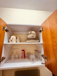 a cupboard with dishes and other items in it at lovely modern 1,2 bedroom apartment in town in Nakuru