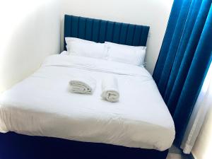 a white bed with two towels on top of it at lovely modern 1,2 bedroom apartment in town in Nakuru