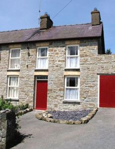 a brick house with two red doors at Bryn-y-Gof in Llwyn-Dafydd