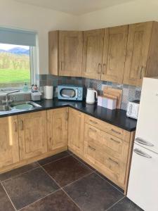 a kitchen with wooden cabinets and a white refrigerator at The Loft - Shemara in Greencastle
