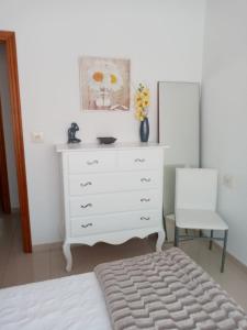 1 dormitorio con cómoda blanca y silla en Apartamento Combarro Ángeles, en Combarro