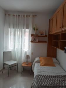 1 dormitorio con 1 cama, 1 silla y 1 ventana en Apartamento Combarro Ángeles, en Combarro