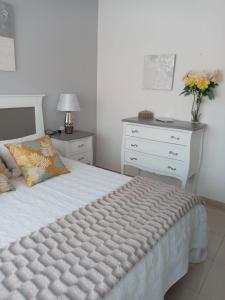 1 dormitorio con 1 cama blanca y un jarrón de flores en Apartamento Combarro Ángeles, en Combarro