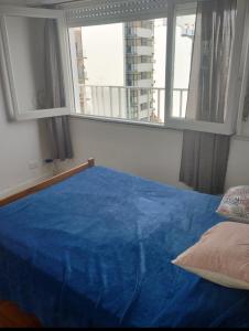 Un dormitorio con una cama azul y una ventana en Alsina 2300 Depto 2 ambientes con terraza propia en Mar del Plata