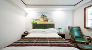 sypialnia z łóżkiem i zielonym krzesłem w obiekcie Nostalgia Hotel Beijing - Tian'anmen Square w Pekinie