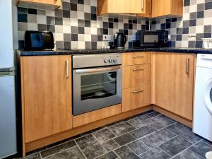 a kitchen with wooden cabinets and an oven at Cosy Penicuik Apartment in Penicuik