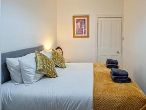Un dormitorio con una cama blanca con almohadas. en Cosy Penicuik Apartment en Penicuik