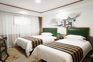 a hotel room with two beds and a painting on the wall at Nost algia Hotel Beijing Tiananmen Square & Qianmen Subway St ation 时光漫步酒店 北京天安门广场前门地铁站店 Free laundry service in Beijing +50 photos