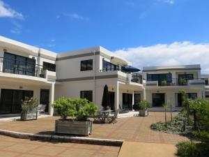 a large white house with a courtyard at Ocean Breeze Resort Pauanui in Pauanui