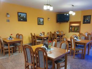 a restaurant with wooden tables and chairs and a tv at Penzion Adak in Párnica
