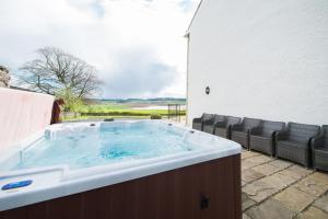 a large hot tub on a patio with chairs at Balmeadowside Farmhouse with Hot Tub in Cupar