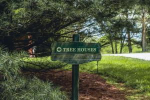 a green tree house sign in the grass at Lofty Willows Treehouse by Amish Country Lodging in Millersburg