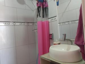 baño con lavabo y cortina de ducha rosa en Lindo Duplex à 50 metros da praia en Imbé