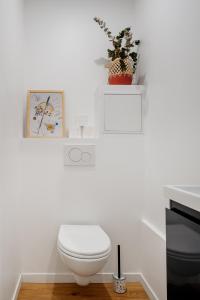 a white bathroom with a toilet and a plant at Edgar Suites Martyrs - Lebas in Paris