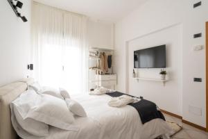 a white bedroom with a bed with white pillows at Hotel Adriatica con Piscina in Riccione