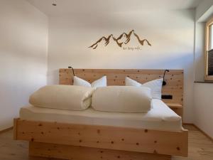 ein Schlafzimmer mit einem Holzbett mit weißen Kissen in der Unterkunft WALD-Apart am Rosenhof in Nauders