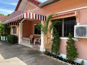 ein rosafarbenes Haus mit einer Markise und einer Veranda in der Unterkunft H&Q 1BR Cozy House, Bangtao Beach in Ban Thalat Choeng Thale
