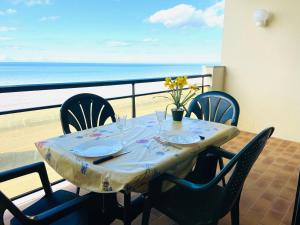 a table with chairs and a view of the beach at Studio lumineux face mer à Cayeux sur mer in Cayeux-sur-Mer