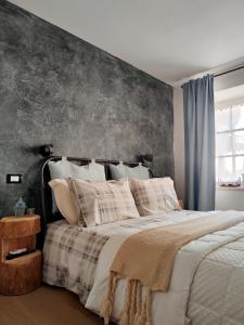 - une chambre avec un grand lit et un mur gris dans l'établissement Stanza Allegra Soave, à Soave