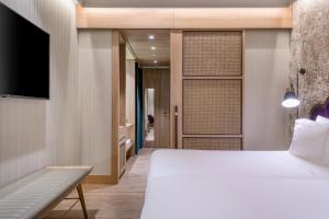 a bedroom with a white bed and a television at Querencia de Sevilla, Autograph Collection in Seville