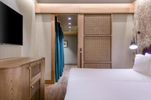 a bedroom with a bed and a flat screen tv at Querencia de Sevilla, Autograph Collection in Seville