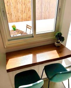 einen Schreibtisch mit zwei grünen Stühlen vor einem Fenster in der Unterkunft Pninat Hadrom in Be’er Scheva
