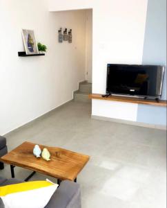 ein Wohnzimmer mit einem Couchtisch und einem Flachbild-TV in der Unterkunft Pninat Hadrom in Be’er Scheva