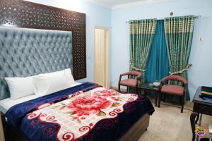 Capry Guest House في كراتشي: غرفة نوم بسرير ولحاف ورد وكرسيين