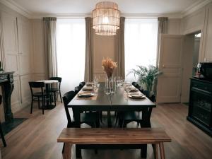 a dining room with a table and a chandelier at La suite in Sainte-Mère-Église