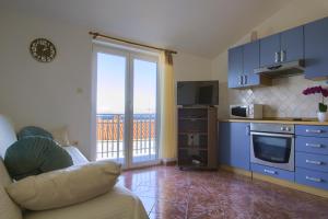 a living room with a couch and a kitchen with blue cabinets at Beachfront Summer Oasis Preko in Preko