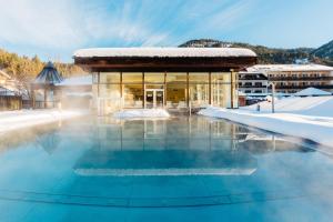 un edificio con piscina nella neve di OptimaMed Gesundheitsresort Weißbriach GmbH a Weissbriach