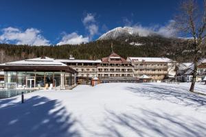 um grande edifício na neve com uma montanha em OptimaMed Gesundheitsresort Weißbriach GmbH em Weissbriach