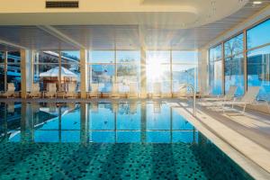 a swimming pool in a building with a large window at OptimaMed Gesundheitsresort Weißbriach GmbH in Weissbriach