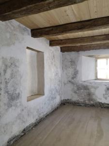 an unfinished room with two windows and a wooden floor at Historisches Townhouse in Prad in Prato allo Stelvio