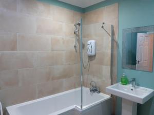 een badkamer met een bad, een wastafel en een douche bij Blackpool Abode - Caxton Lodge in Blackpool