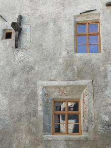 a building with two windows and a cross on it at Historisches Townhouse in Prad in Prato allo Stelvio