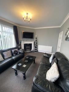 a living room with a black leather couch and a coffee table at Blackpool Abode - Caxton Lodge in Blackpool