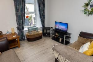 a living room with a couch and a flat screen tv at Au Centre-Ville in Lisnaskea