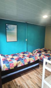 Duas camas num quarto com paredes azuis em Manta Ray's Cahuita Apart. em Cahuita
