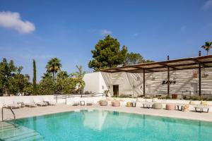 a swimming pool with chairs and a building at Kimpton Aysla Mallorca by IHG in Santa Ponsa