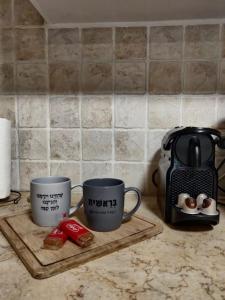 two coffee mugs and a toaster on a kitchen counter at Garden House By IsrApart in Ra‘ananna