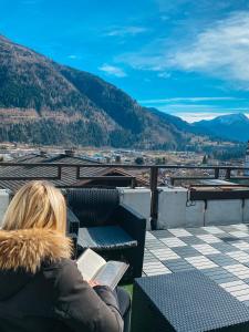 a woman sitting on a balcony reading a book at Appartamento panoramico in Sùtrio