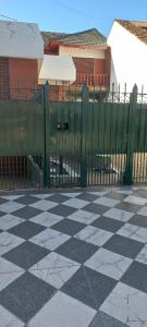 une clôture devant un bâtiment avec un sol en damier dans l'établissement Casa Privada Monte Grande y cochera, à Monte Grande