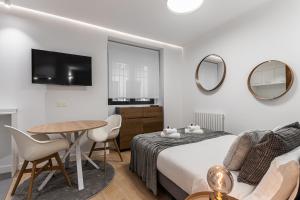 een slaapkamer met een bed en een tafel en een televisie bij BNBHolder The Sweetest II Centre in Madrid