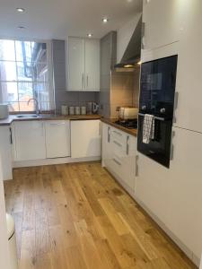 cocina con armarios blancos y suelo de madera en HU1 Triplex City Centre Gem sleeps 6 H7, en Hull