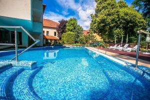 une grande piscine bleue avec des chaises à côté d'un bâtiment dans l'établissement Bassiana Hotel es Etterem, à Sárvár